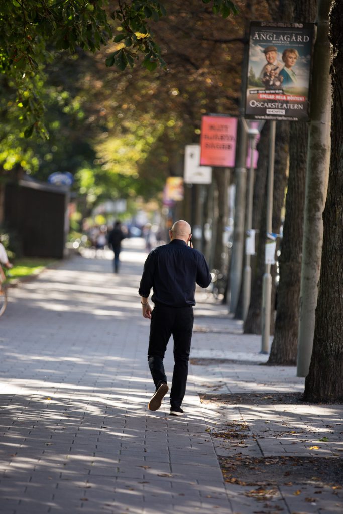 Johan Mossberg promenerar längs trottoar med träd
